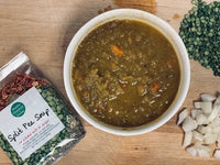 Split pea soup in a bowl with ingredients on a wooden surface
