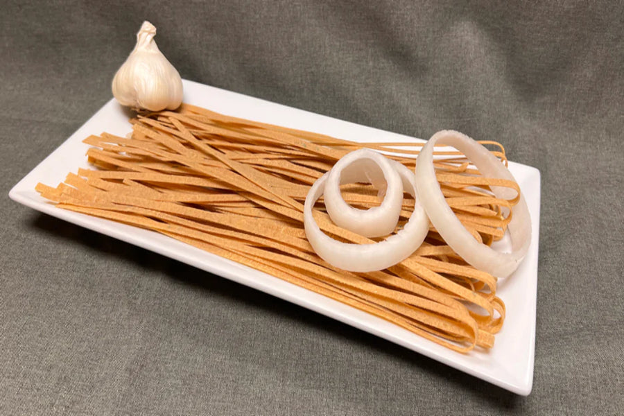 Pasta and garlic on a white plate with a gray background