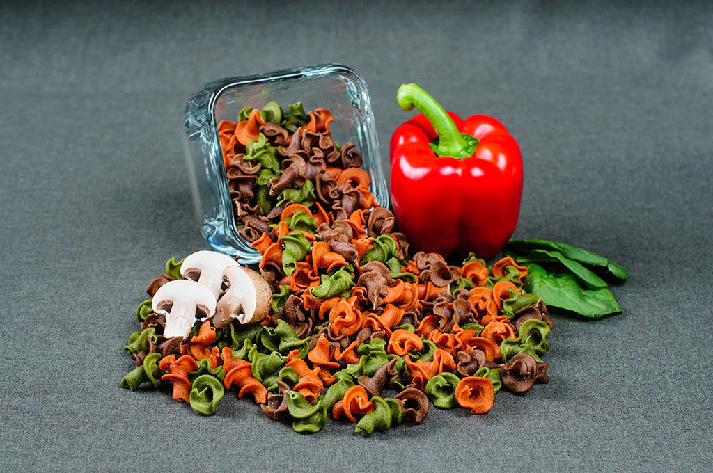 Colorful pasta with a red pepper and mushrooms on a gray background