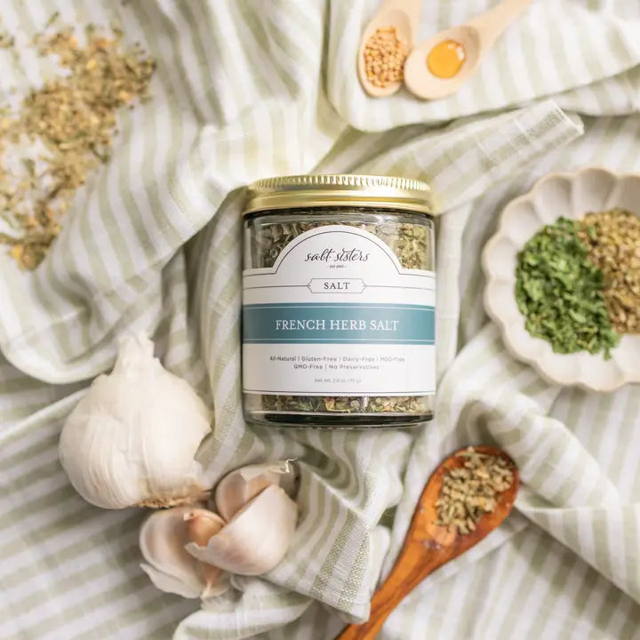 Jar of French Herb Salt with garlic and herbs on a striped fabric background